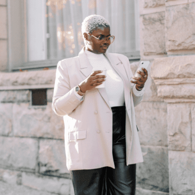 Woman looking at her phone with a coffee in her hand