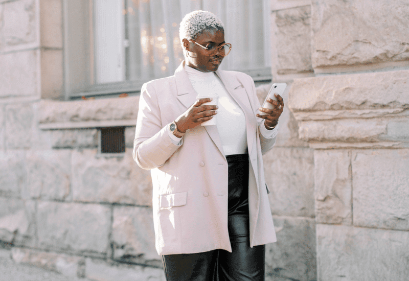 Woman looking at her phone with a coffee in her hand