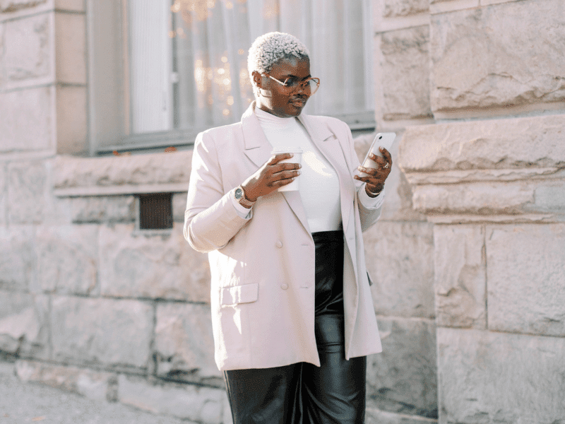 Woman looking at her phone with a coffee in her hand